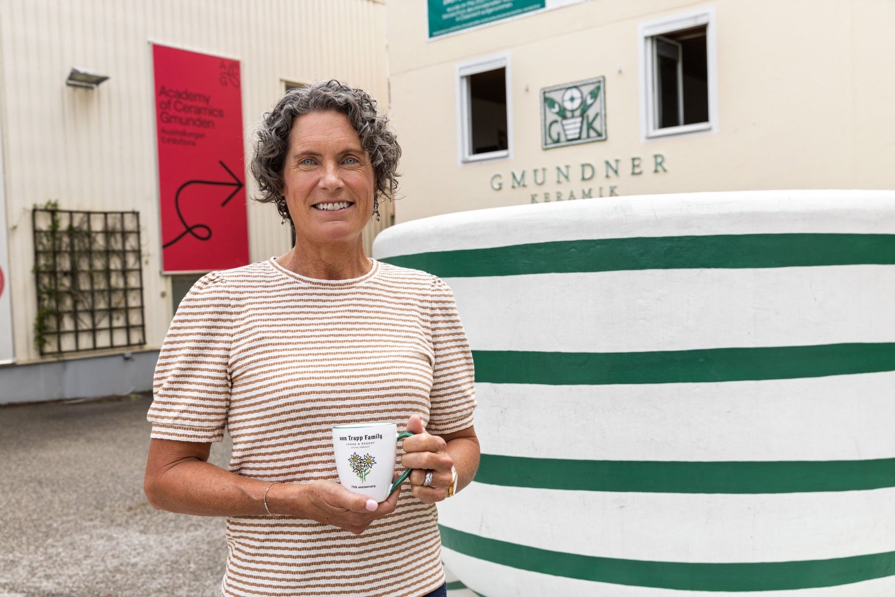 Kristina von Trapp outside the Gmundner Keramik manufactory holding an Edelweiss cup