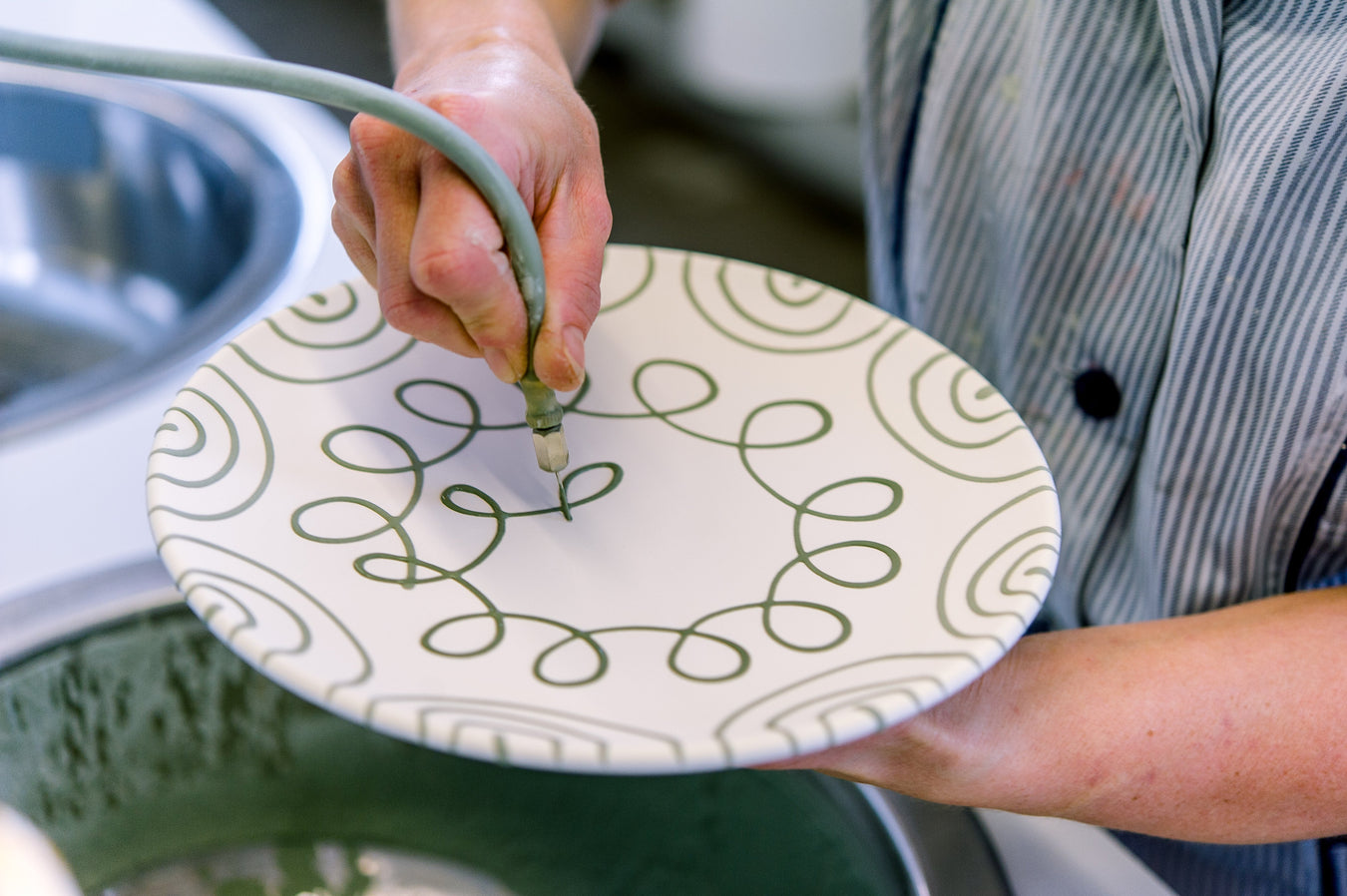 Person holding a decorative plate with a pattern, outdoors.